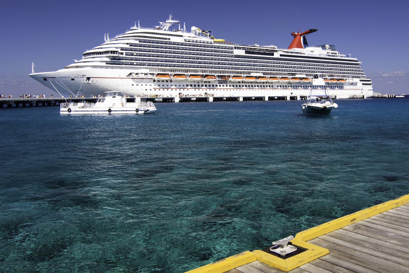 Carnival cruise ship docked at a pier in Cozumel over clear blue water