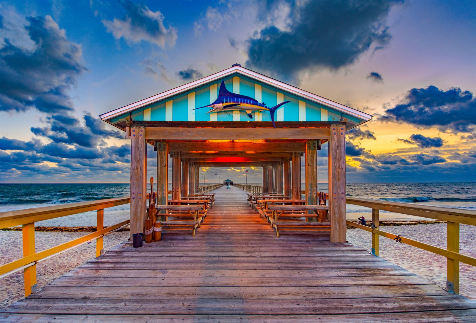 Covered pavilion at the end of a wooden pier under a dramatic sky